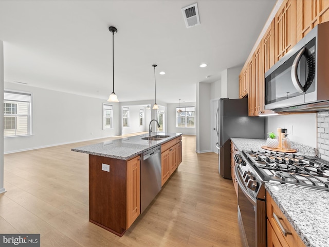 kitchen featuring a kitchen island with sink, stainless steel appliances, visible vents, light wood-style floors, and open floor plan