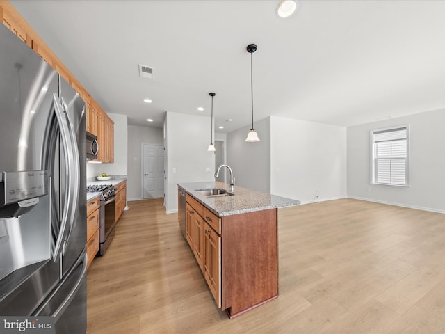 kitchen with a sink, visible vents, light wood-style floors, appliances with stainless steel finishes, and brown cabinetry