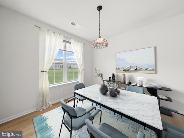 dining space with light wood-style flooring, visible vents, and baseboards