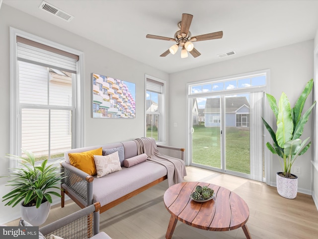 living area with a ceiling fan, light wood-type flooring, visible vents, and baseboards