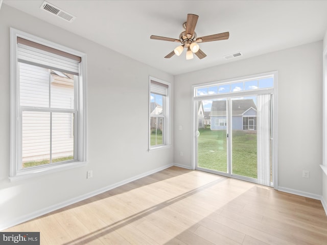 spare room with light wood-style floors, plenty of natural light, and visible vents