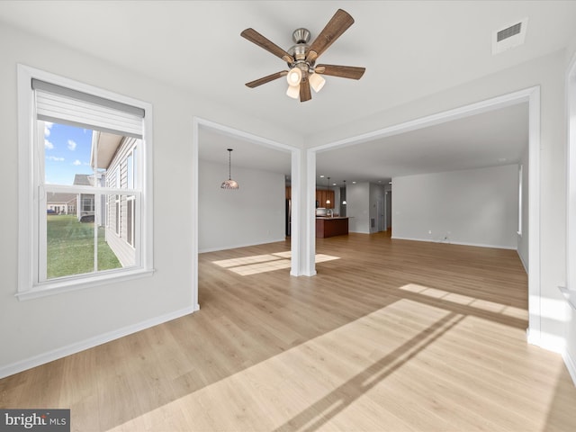 unfurnished living room with light wood-type flooring, ceiling fan, visible vents, and baseboards