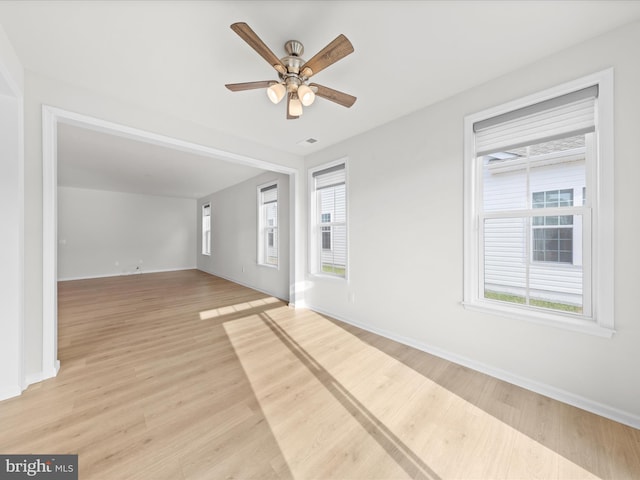 unfurnished room with a healthy amount of sunlight, light wood-style flooring, and baseboards