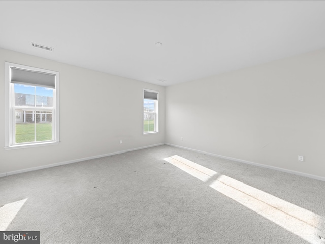 unfurnished room with carpet flooring, visible vents, and baseboards