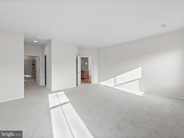 carpeted spare room featuring visible vents and baseboards