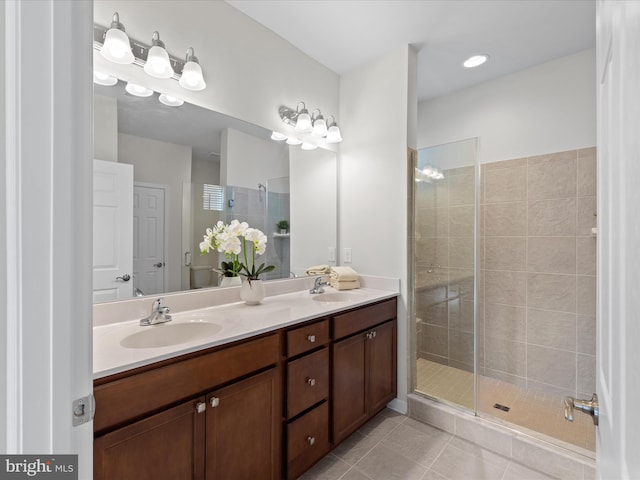 full bath with double vanity, a stall shower, tile patterned flooring, and a sink