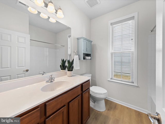 bathroom with a shower, visible vents, toilet, vanity, and wood finished floors