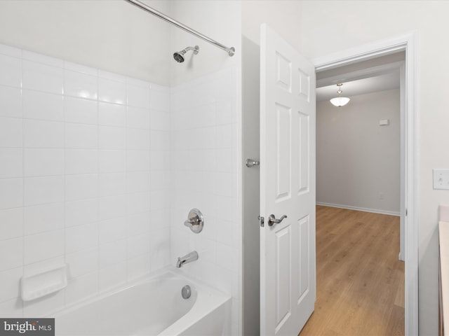 bathroom featuring baseboards, tub / shower combination, and wood finished floors