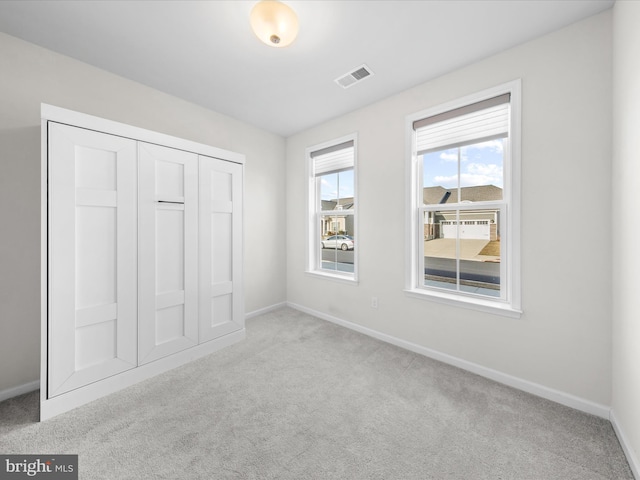 unfurnished bedroom featuring a closet, carpet flooring, visible vents, and baseboards