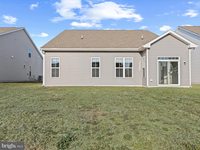 rear view of house featuring central AC, a lawn, and roof with shingles