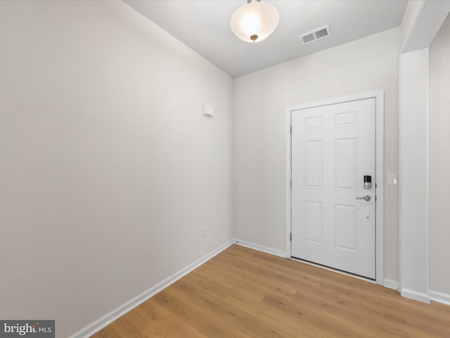 foyer featuring light wood-type flooring, baseboards, and visible vents