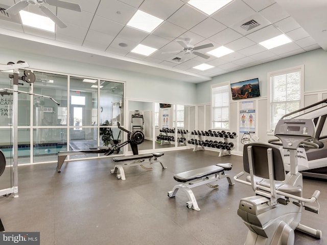 exercise room with a ceiling fan, a paneled ceiling, and visible vents