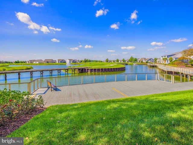 view of dock featuring a lawn, a water view, and a residential view