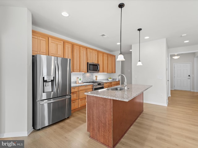 kitchen featuring stainless steel appliances, recessed lighting, light wood-style floors, a sink, and an island with sink