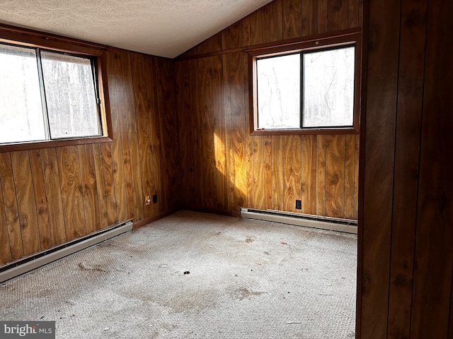 carpeted spare room featuring a baseboard radiator, baseboard heating, vaulted ceiling, wooden walls, and a textured ceiling