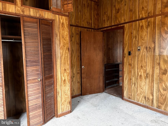 interior space featuring a closet, carpet flooring, and wooden walls