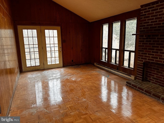 unfurnished room with lofted ceiling, a healthy amount of sunlight, wooden walls, and baseboard heating