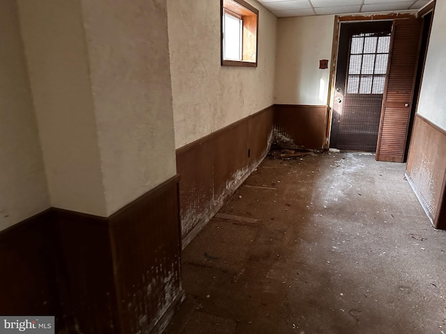 misc room with a paneled ceiling, a wainscoted wall, and wood walls