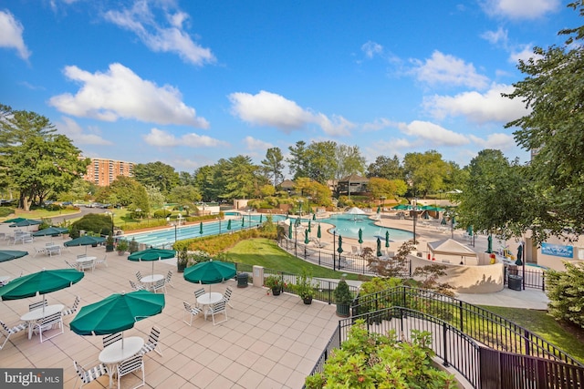 community pool with a patio area and fence