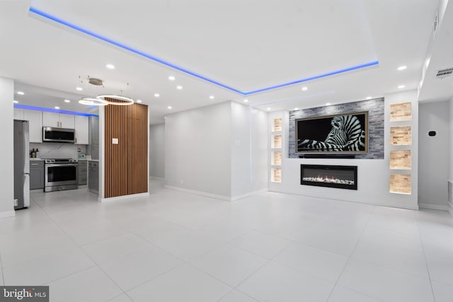 unfurnished living room with recessed lighting, a raised ceiling, visible vents, a large fireplace, and baseboards