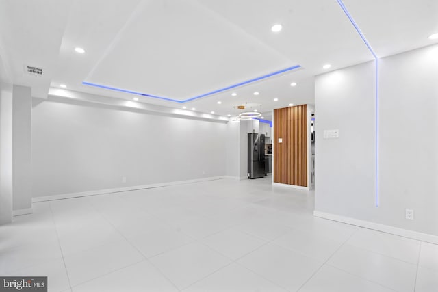 empty room with visible vents, baseboards, a raised ceiling, and recessed lighting