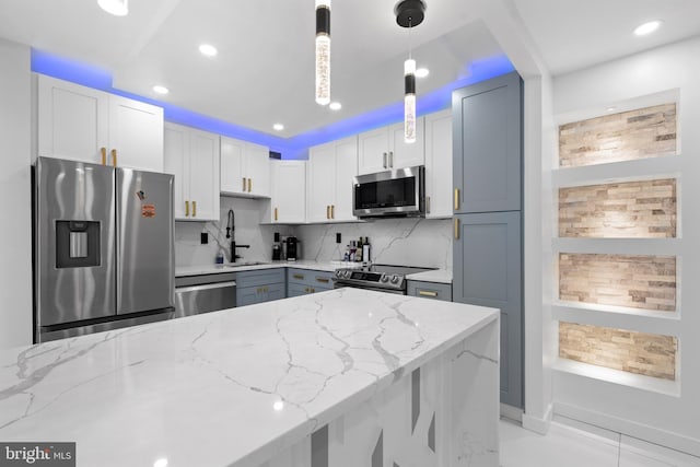 kitchen with a sink, appliances with stainless steel finishes, light stone countertops, tasteful backsplash, and pendant lighting