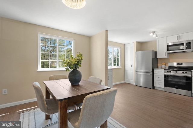 dining space with light wood finished floors and baseboards