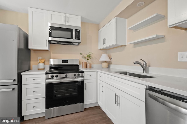 kitchen featuring open shelves, a sink, light countertops, white cabinets, and appliances with stainless steel finishes