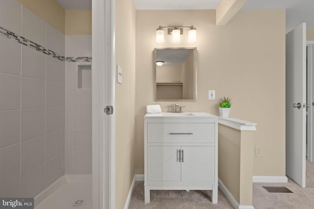 full bath featuring visible vents, baseboards, vanity, and a tile shower