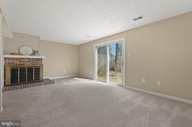 unfurnished living room featuring visible vents, a fireplace, a textured ceiling, and carpet