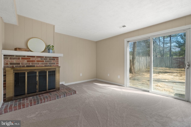 unfurnished living room featuring visible vents, a textured ceiling, carpet floors, a fireplace, and baseboards