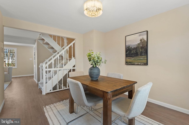 dining room featuring stairway, a notable chandelier, wood finished floors, and baseboards