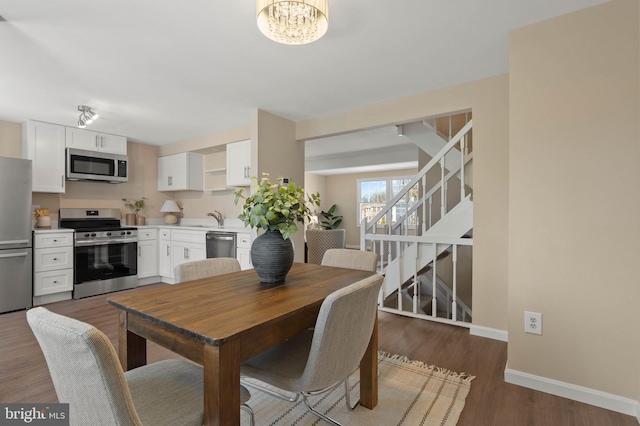 dining space featuring baseboards, an inviting chandelier, wood finished floors, and stairs