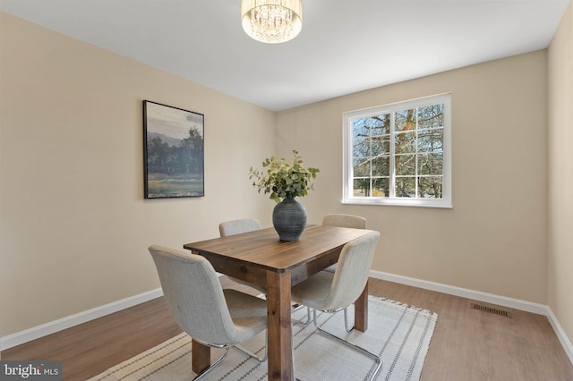 dining room with visible vents, baseboards, wood finished floors, and a chandelier