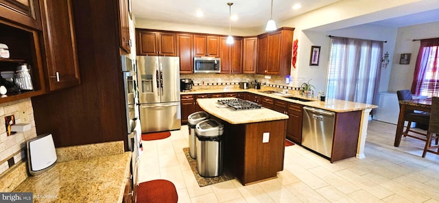 kitchen with stainless steel appliances, a peninsula, a center island, tasteful backsplash, and pendant lighting