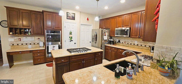 kitchen featuring stainless steel appliances, decorative light fixtures, a sink, and light stone counters