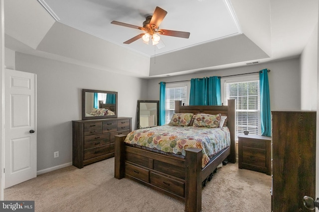 carpeted bedroom with a tray ceiling, a ceiling fan, visible vents, and baseboards