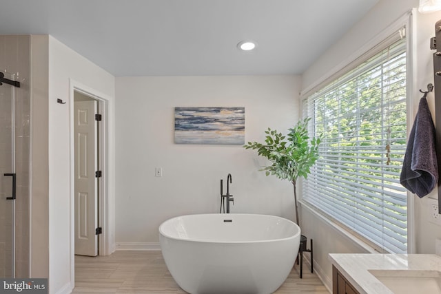 bathroom featuring a soaking tub, a shower stall, baseboards, and vanity