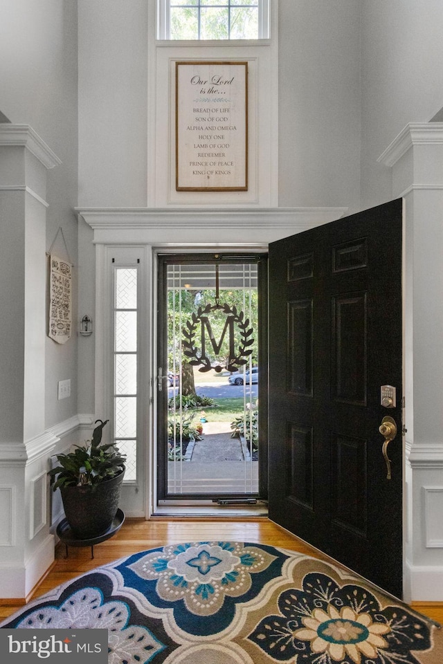 foyer entrance featuring a high ceiling, wood finished floors, and decorative columns