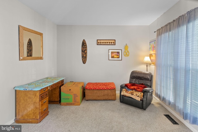 living area featuring carpet floors, plenty of natural light, visible vents, and baseboards