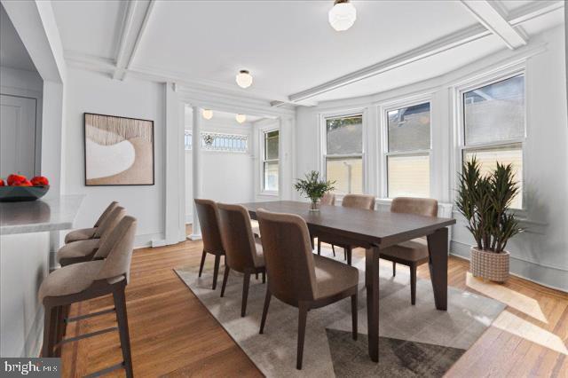 dining space with beamed ceiling and wood finished floors