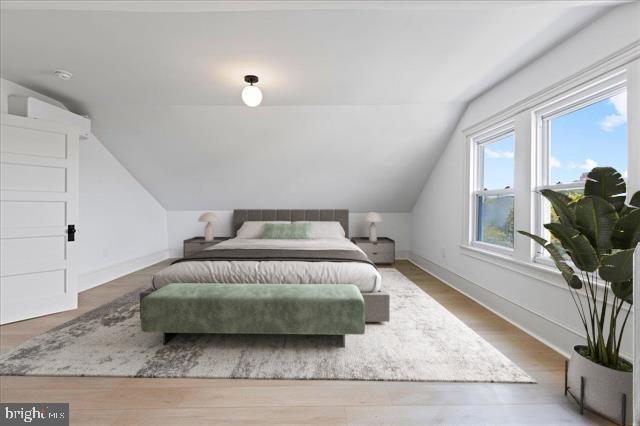 bedroom with baseboards, vaulted ceiling, and wood finished floors