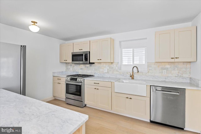 kitchen with stainless steel appliances, backsplash, a sink, and light countertops