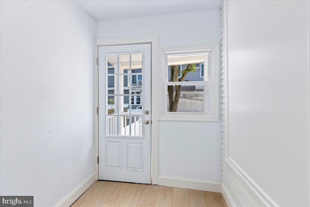 doorway with baseboards and light wood-style floors