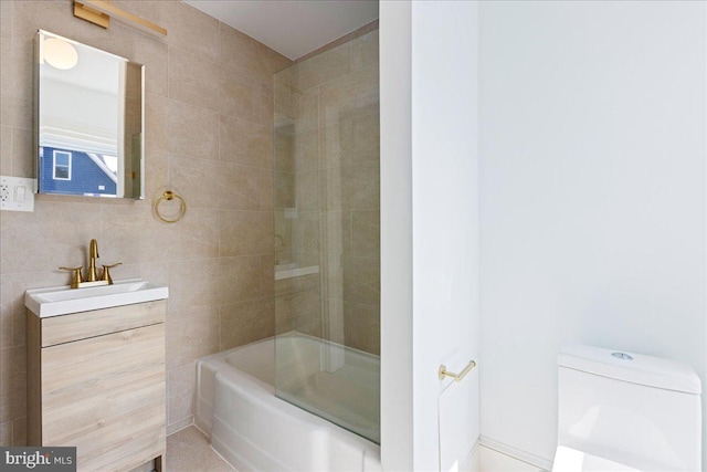 bathroom with  shower combination, vanity, toilet, and tile walls