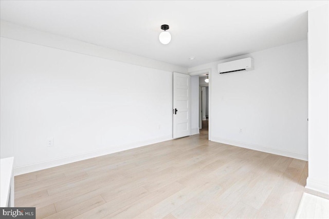 empty room with baseboards, a wall unit AC, and light wood-style floors