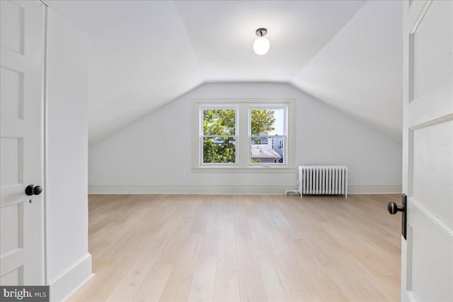 additional living space featuring lofted ceiling, baseboards, light wood-style flooring, and radiator