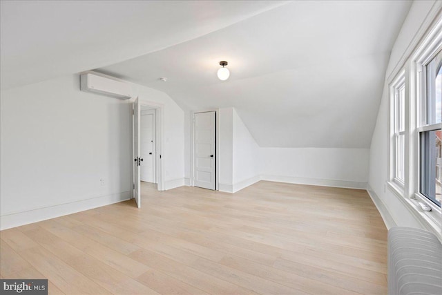 bonus room featuring lofted ceiling, radiator, a wall mounted AC, light wood-style floors, and baseboards