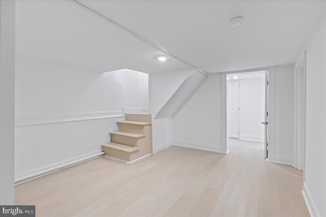 additional living space with baseboards, stairway, and wood finished floors