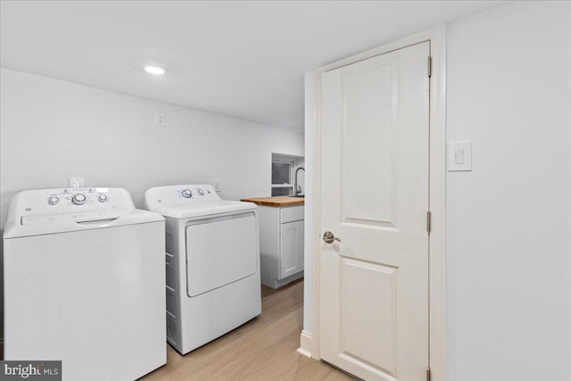 washroom featuring light wood-style floors, washer and dryer, and cabinet space